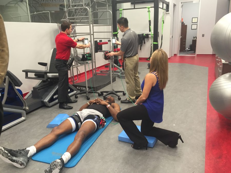 Houston Rockets star Dwight Howard undergoes blood flow restriction training as ESPN's Stephanie Bell (kneeling) observes. (Michael Sciallo/ESPN)